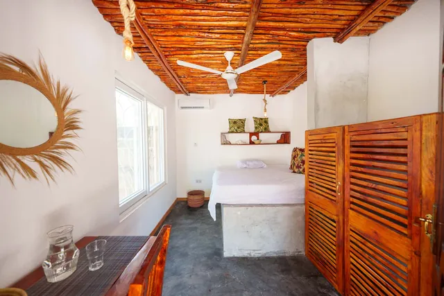 Schlafzimmer im Wohnhaus mit Holzdecke, Deckenventilator und Klimaanlage
