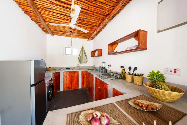 Küche im Wohnhaus mit Kühlschrank, Holzfronten und Arbeitsplatte