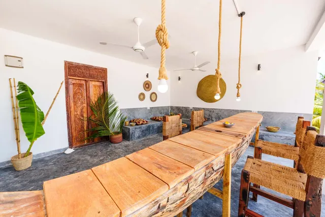 Langer Holztisch mit Stühlen unter Hängeleuchten im Open Living Space