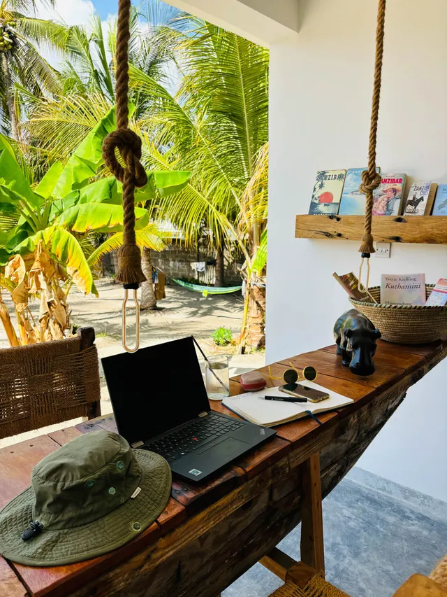 Arbeitsplatz mit Laptop am Holztisch, Blick in den Palmengarten
